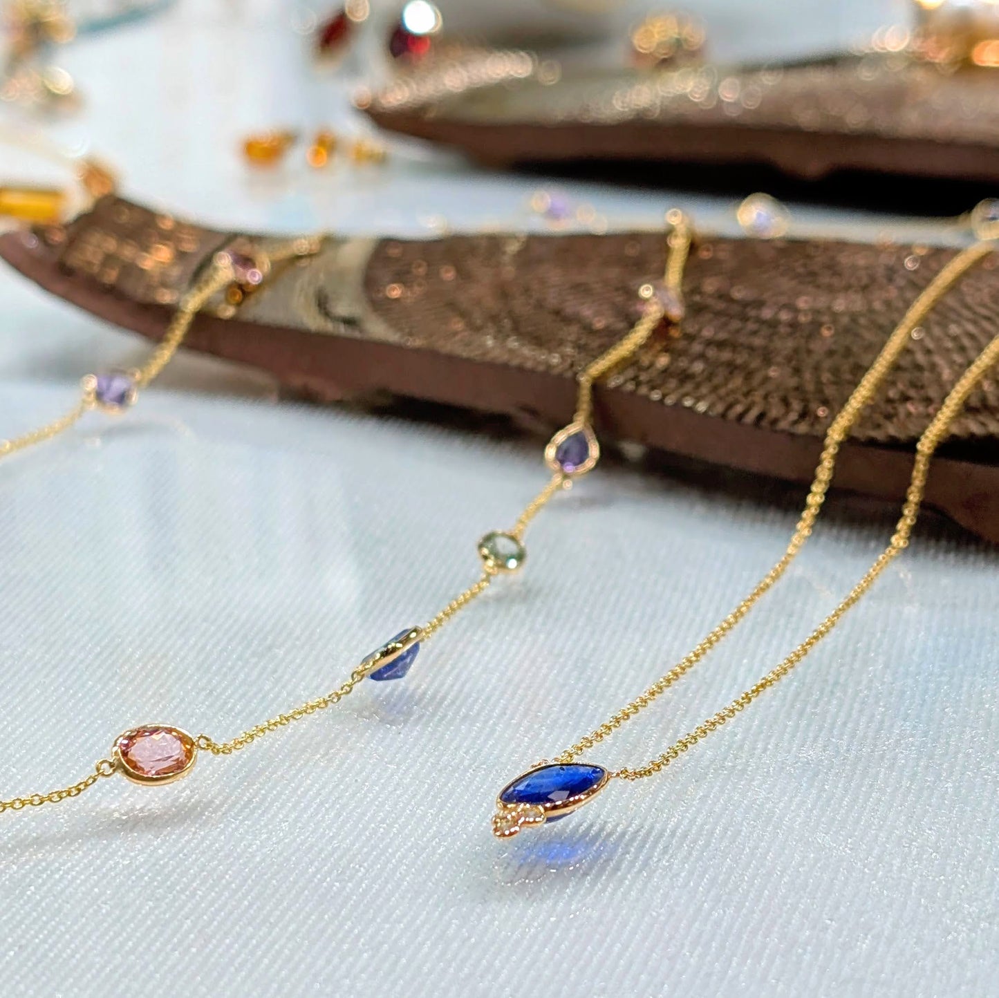 Gold necklace with colorful gemstones on a textured surface