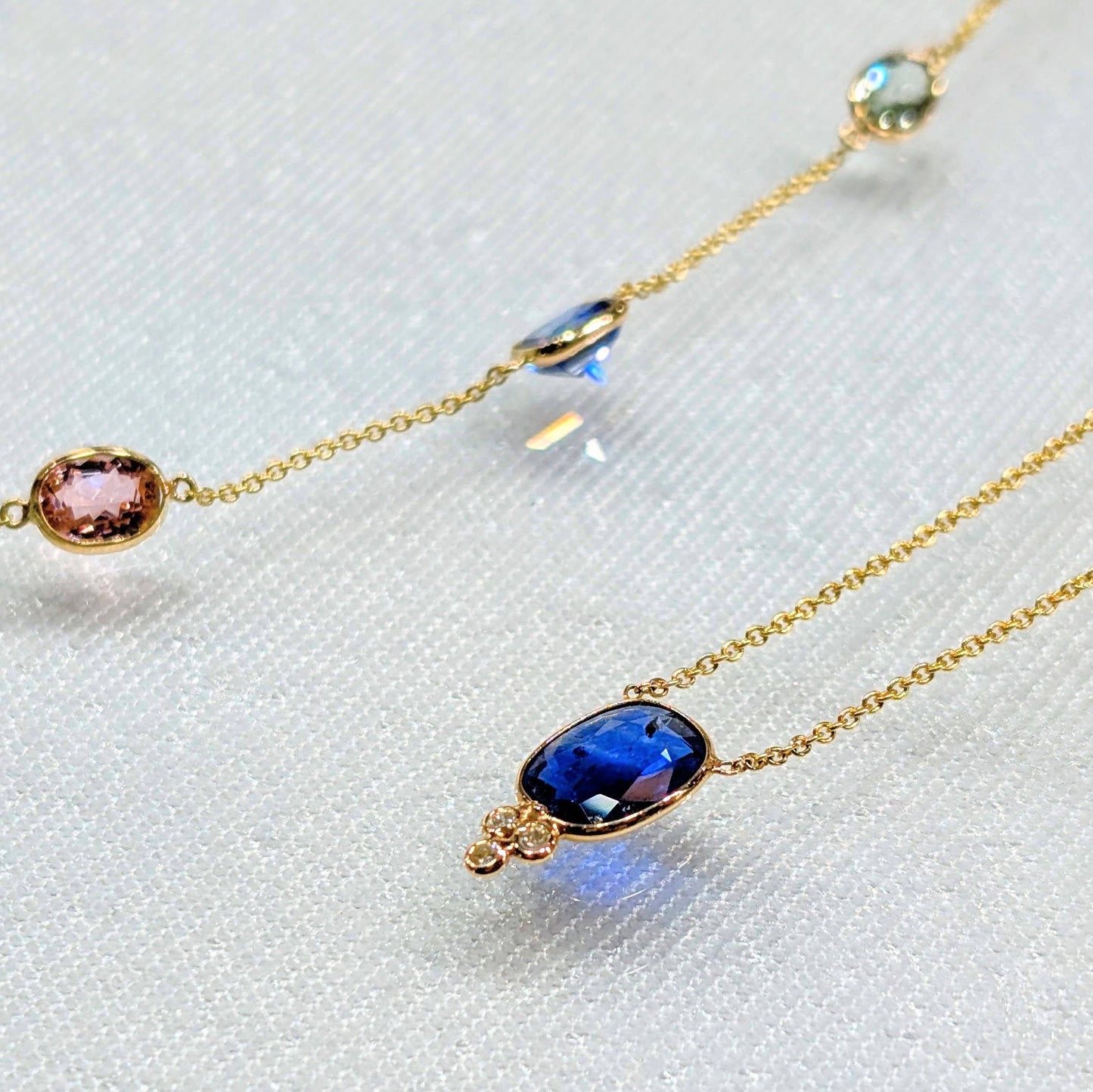 Gold necklaces with gemstones on a white textured background