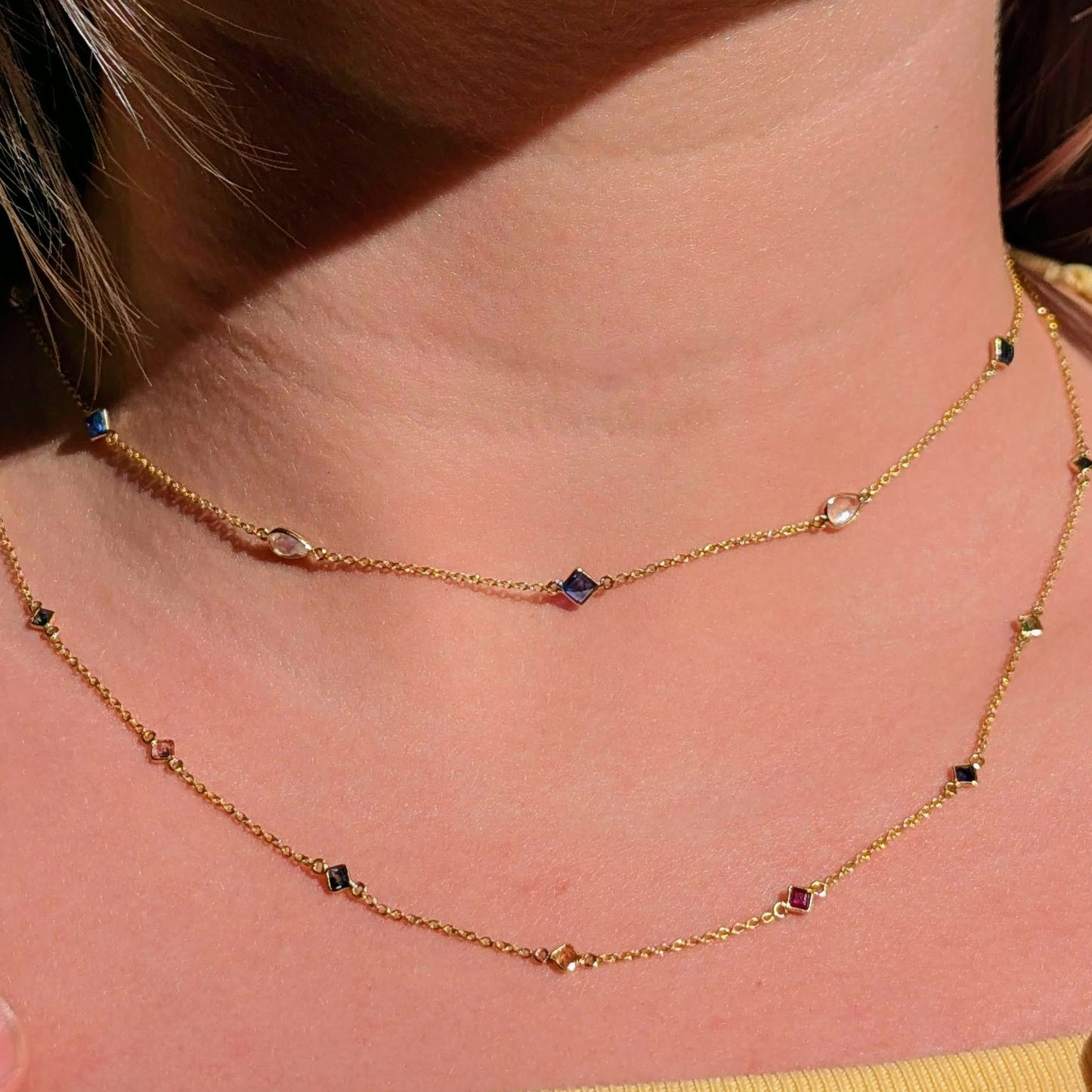 Close-up of a person wearing a delicate gold necklace with small beads.