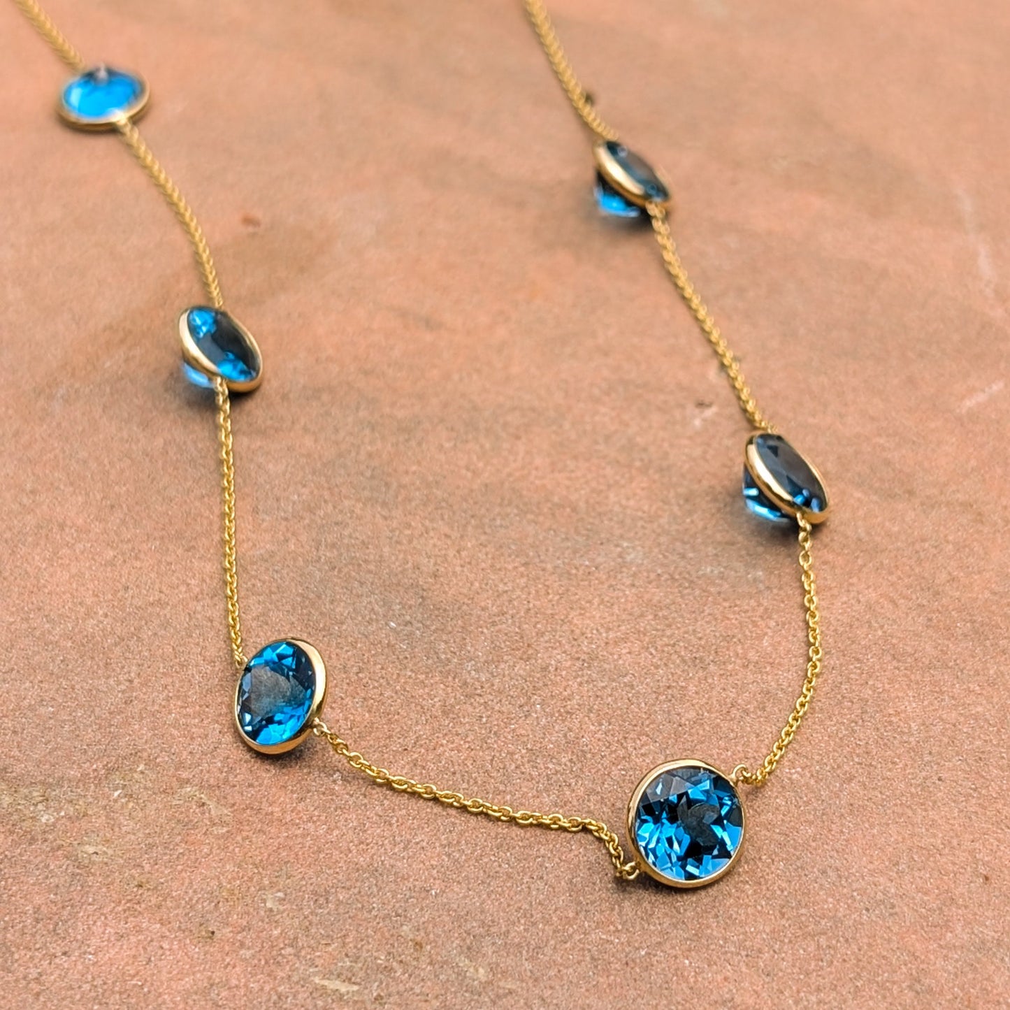 Gold necklace with blue gemstones on a textured surface