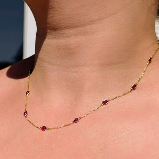Gold necklace with red gemstones on a person's neck