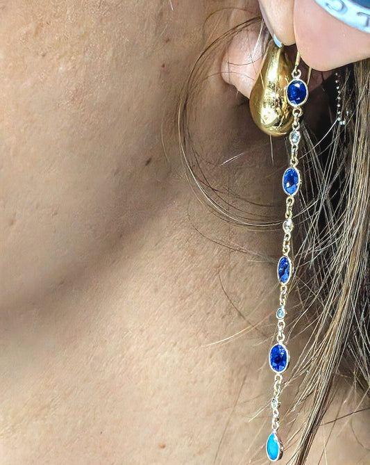 Gold earring with blue sapphires, Diamonds and Turquoise worn by a person
