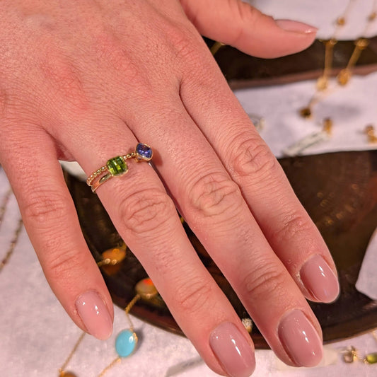 Hand wearing a ring with gemstones on a textured surface