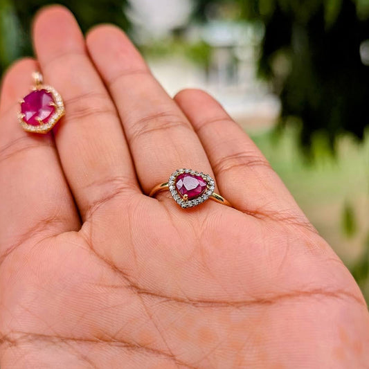 Gold rings with red gemstones on a person's hand against a blurred green background