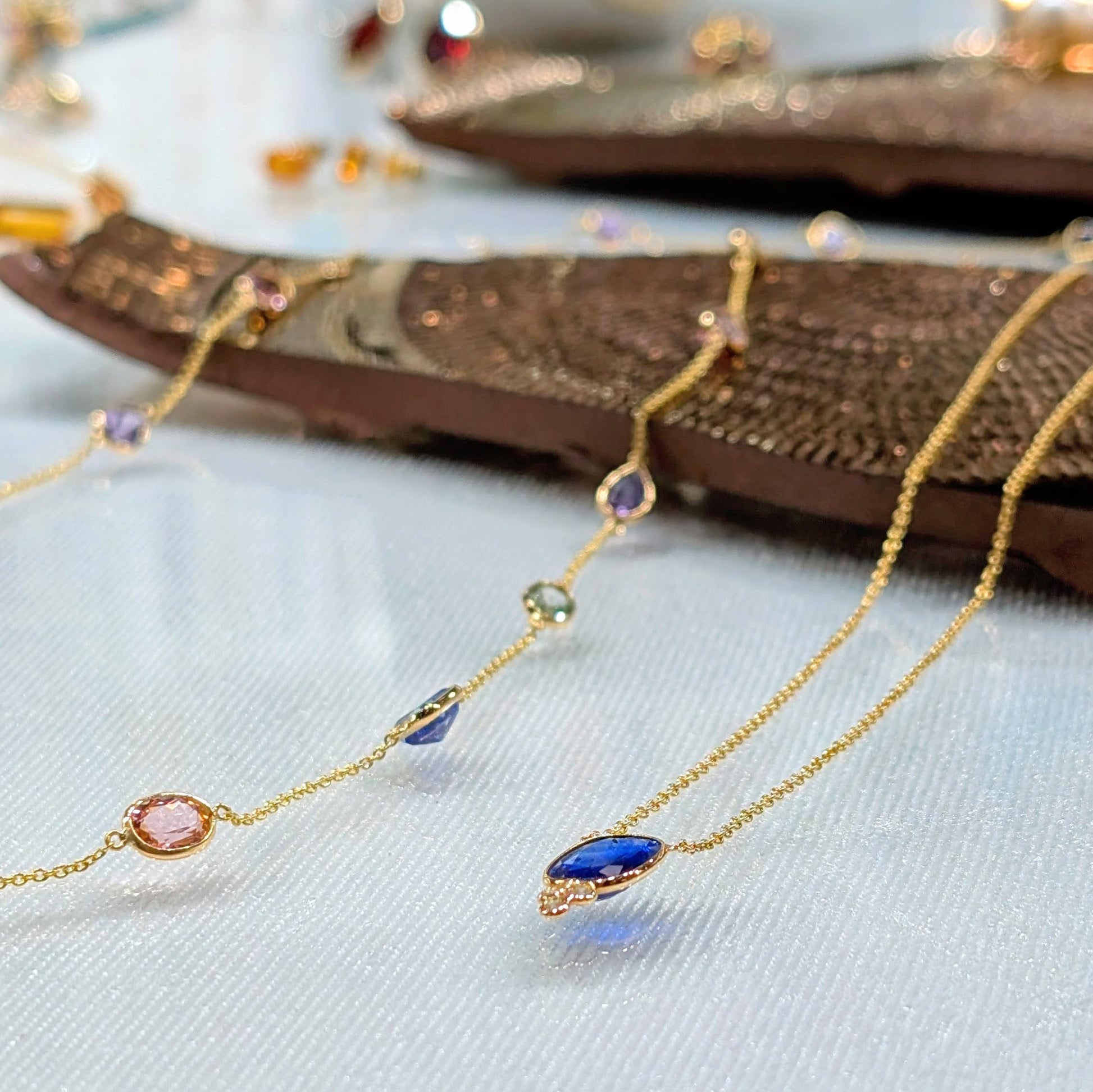 Gold necklace with colorful gemstones on a textured surface