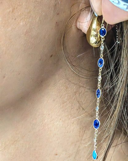 Gold earring with blue sapphires, Diamonds and Turquoise  worn by a person