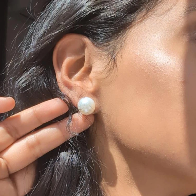 Close-up of a person wearing a pearl earring with a blurred background