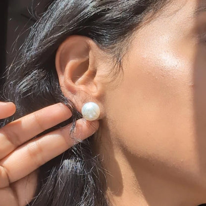 Close-up of a person wearing a pearl earring with a blurred background