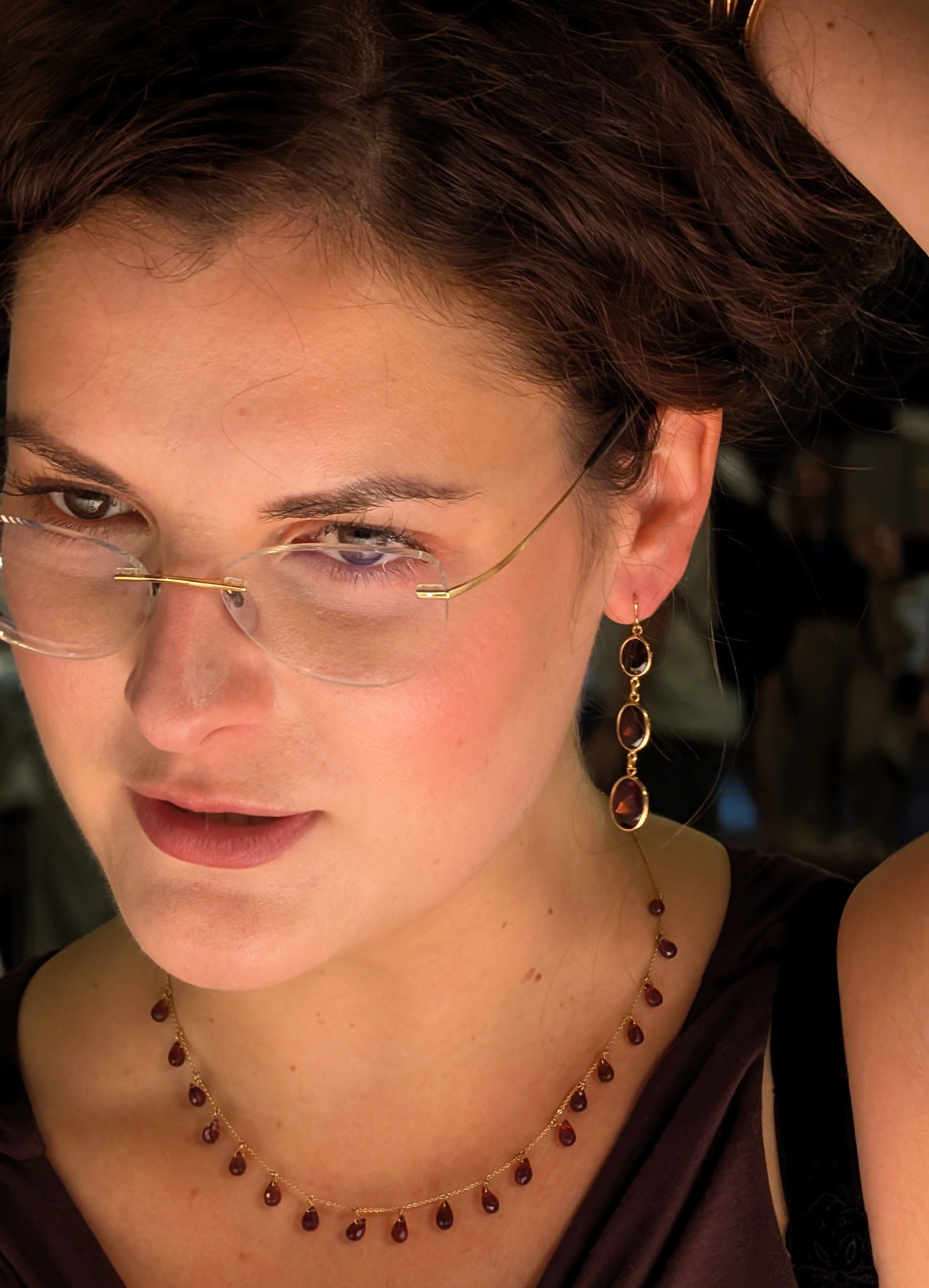 Woman wearing glasses and a necklace with a blurred background