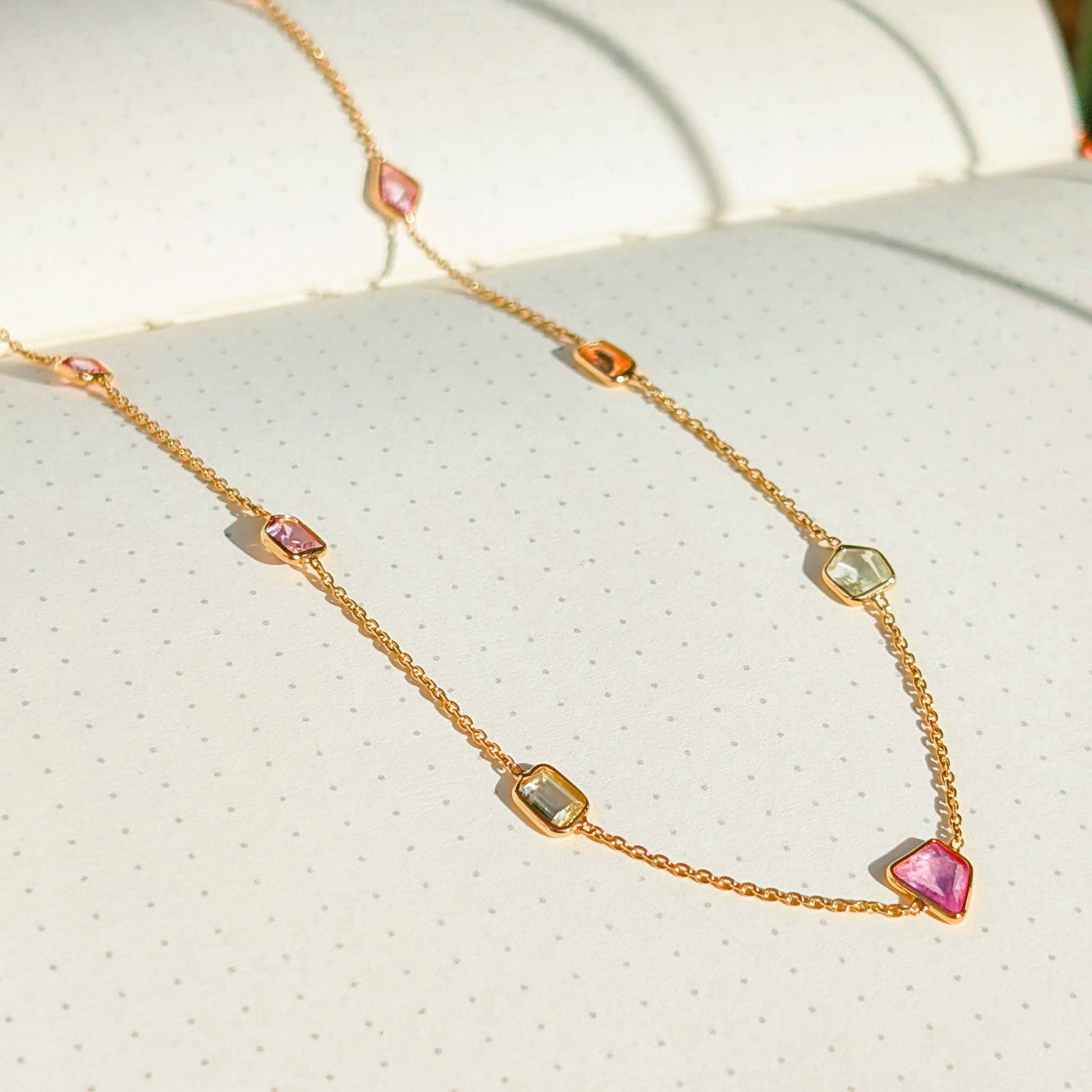 Gold necklace with colorful beads on a textured surface