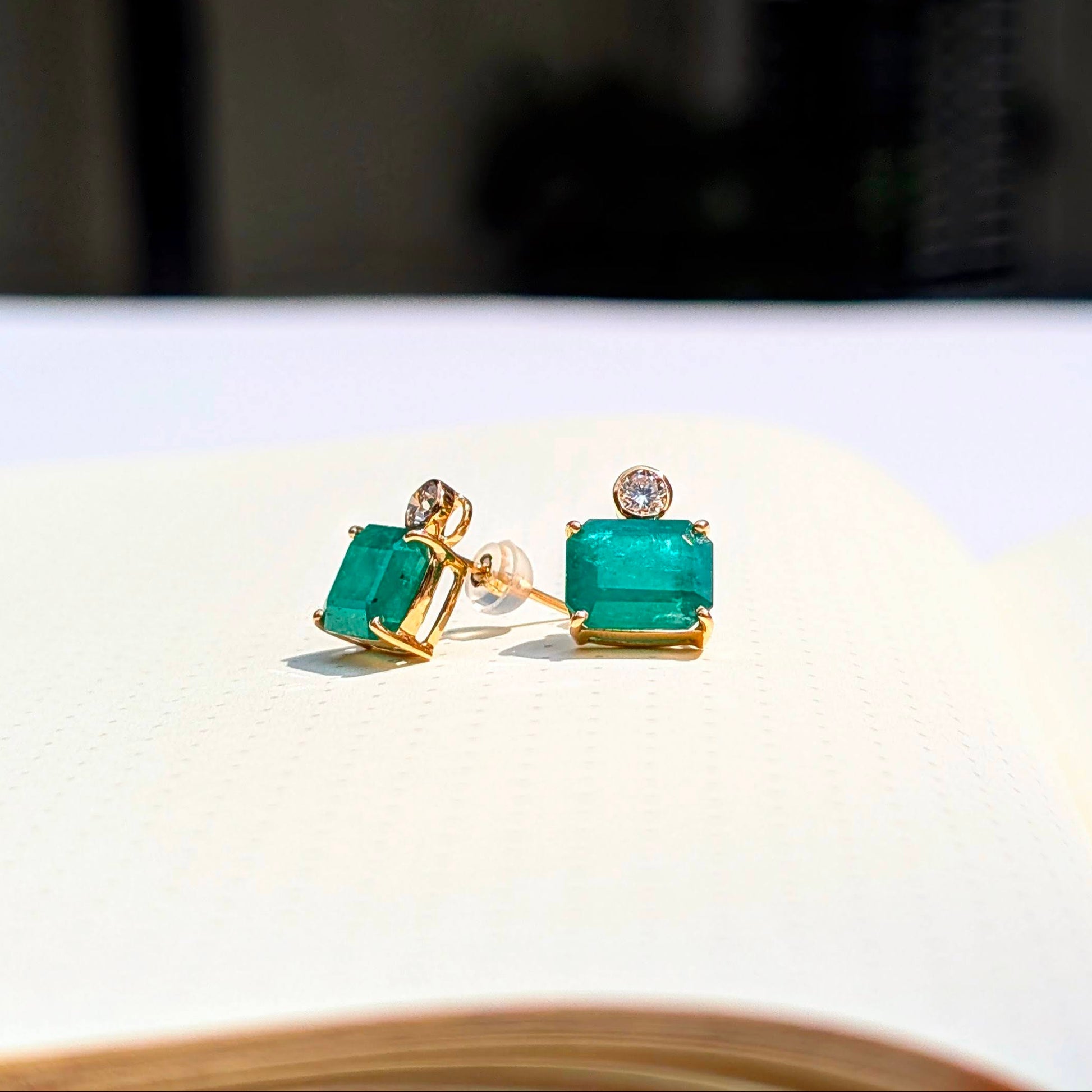 Crafted in solid 18K gold, these refined studs feature vivid baguette-cut emeralds crowned with brilliant round diamonds of exceptional VVS quality.
