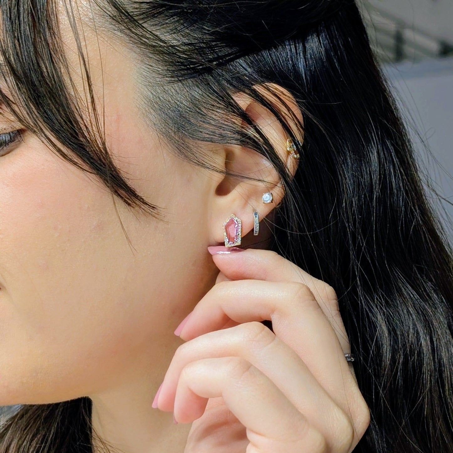 Close-up of a person wearing a pink sapphire studs with diamonds 