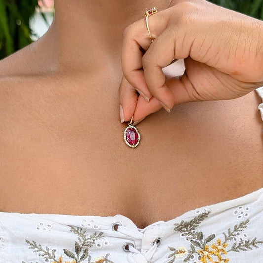 pendant showcases a stunning oval-shaped ruby of exceptional colour and clarity, set in solid 18K gold and framed by a halo of VVS, G-colour diamonds